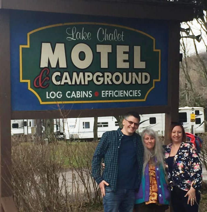 New owners of Lake Chalet in front of welcome sign