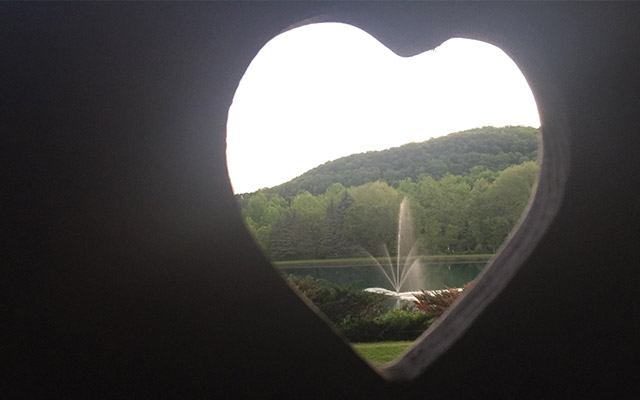 view of campground lake and fountain through heart shaped cutout.